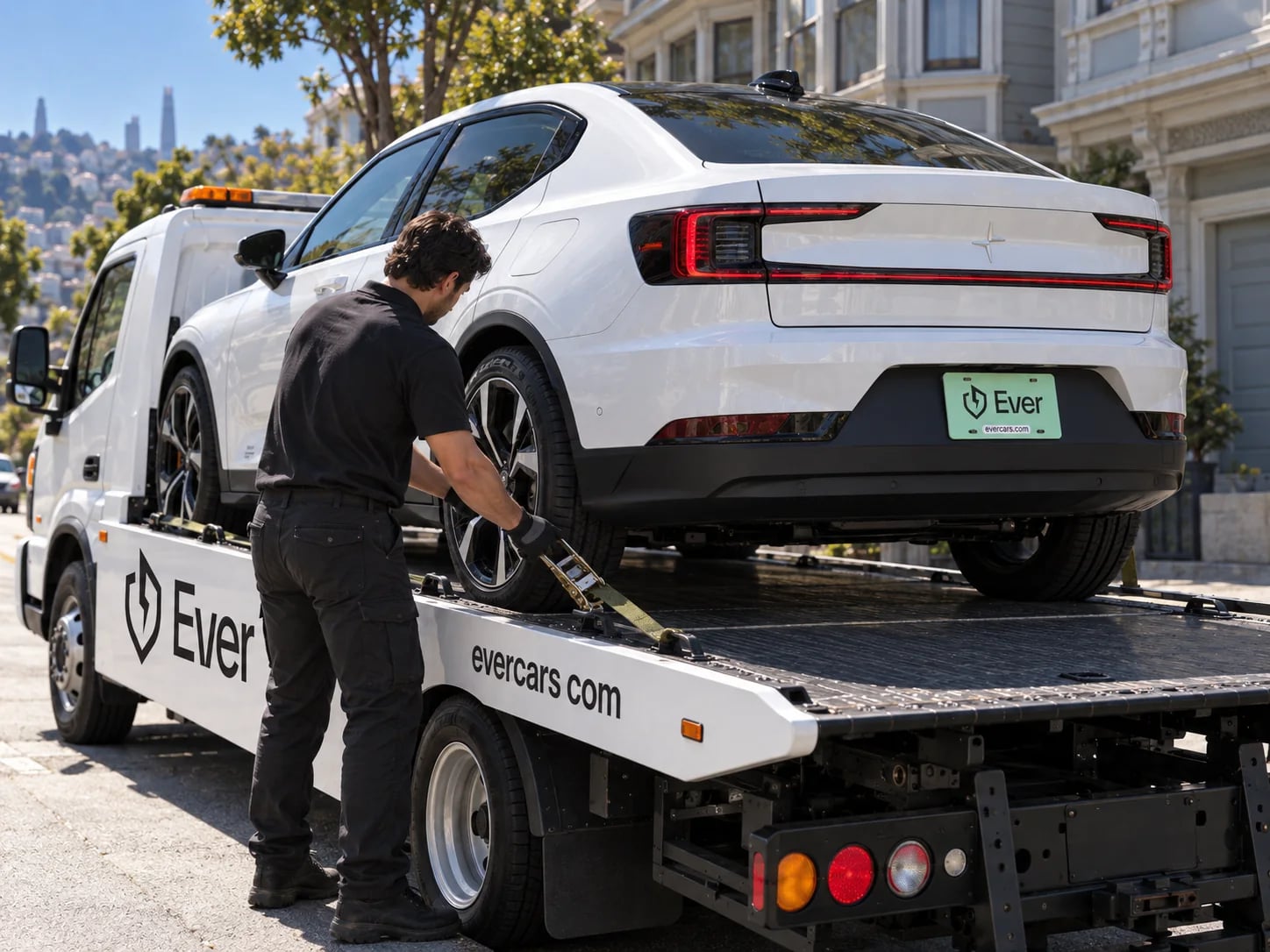 An Ever driver ratcheting the strap on a white EV loaded onto the Ever flatbed