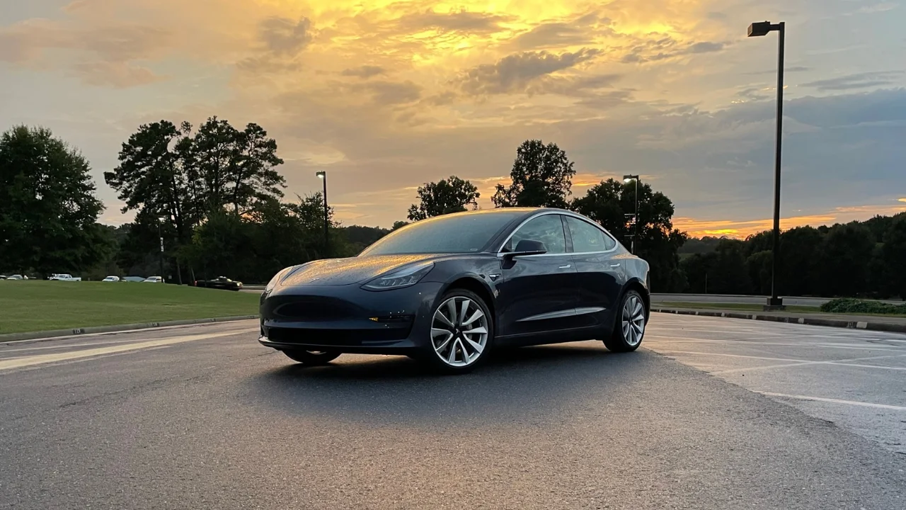 Tesla Model 3 parked underneath the sunset.